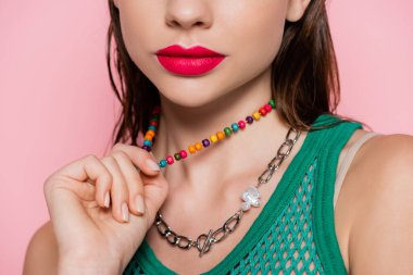 cropped view of young model with bright makeup posing while pulling necklace isolated on pink 