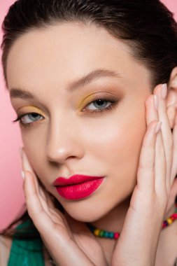 close up of young model with bright makeup looking at camera isolated on pink 