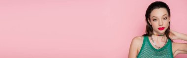 young model with bright makeup posing while looking at camera isolated on pink, banner 