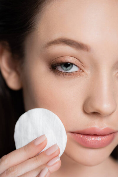 close up view of cropped young woman removing makeup with cotton pad
