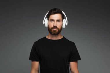 bearded man in wireless headphones listening music isolated on grey