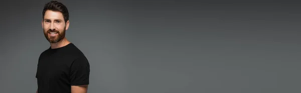 Портрет Улыбающегося Бородатого Мужчины Черной Футболке Смотрящего Камеру Изолированную Сером — стоковое фото