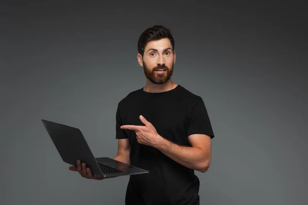 Amazed Bearded Man Black Shirt Pointing Finger Laptop Isolated Grey — Stockfoto