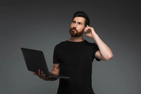 Pensive Freelancer Beard Holding Laptop Looking Away Isolated Grey — Zdjęcie stockowe