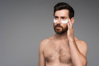 shirtless and bearded man with moisturizing eye patches isolated on grey 