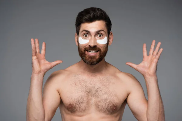 Excited Bearded Man Moisturizing Eye Patches Gesturing Isolated Grey — Stockfoto