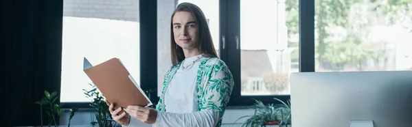 Young Queer Designer Holding Paper Folder Looking Camera Computer Office — Foto Stock