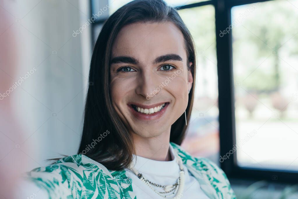Portrait of cheerful queer designer looking at camera in creative agency 