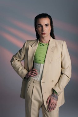 Trendy nonbinary person in suit posing on abstract background 