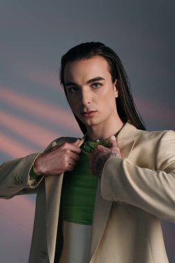 Portrait of trendy queer person wearing jacket on abstract background 