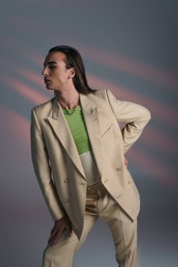 Side view of nonbinary person in suit standing on abstract background 