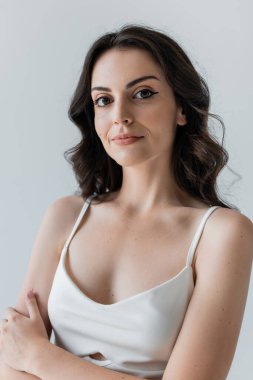 Portrait of brunette model looking at camera isolated on grey 