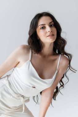 Trendy woman with makeup looking at camera isolated on grey 