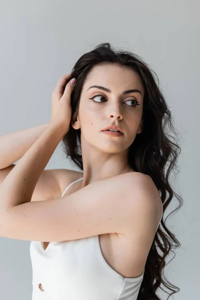 Young Woman Touching Brunette Hair Looking Away Isolated Grey — Stockfoto