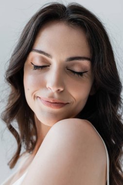 Portrait of young woman with makeup standing with closed eyes isolated on grey 