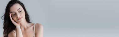 Brunette woman with closed eyes standing isolated on grey, banner 