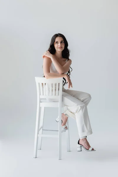 Full Length Stylish Woman Touching Shoulder While Sitting Chair Grey — Fotografia de Stock