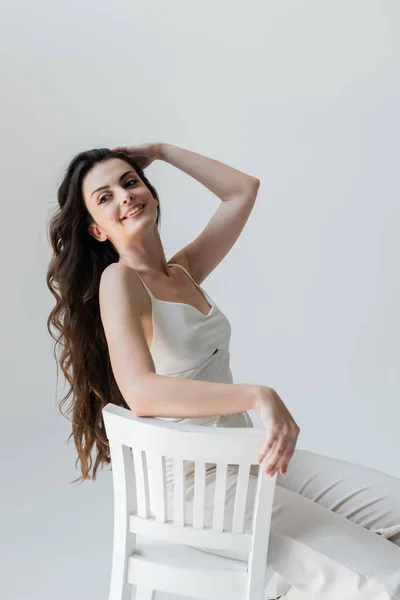 Positive Long Haired Woman Sitting White Chair Isolated Grey — Foto de Stock