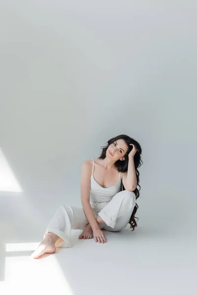 Long Haired Barefoot Woman White Clothes Looking Camera Grey Background — Stock Fotó