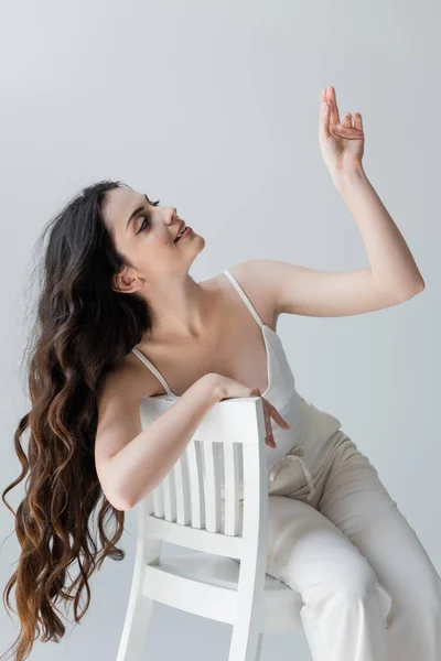 Stylish Long Haired Woman Gesturing While Sitting Chair Isolated Grey — Stock fotografie