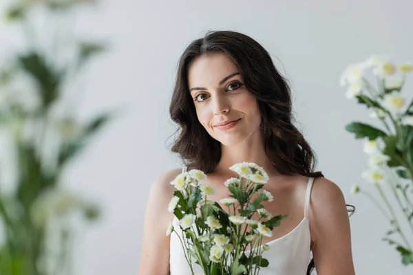 Smiling Woman White Top Looking Camera Blurred Flowers Isolated Grey — Stok fotoğraf