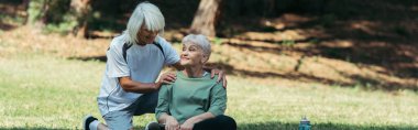 cheerful senior man hugging wife with grey hair sitting in green park, banner