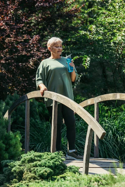 Full Length Sportive Senior Woman Holding Sports Bottle Standing Bridge — Stockfoto