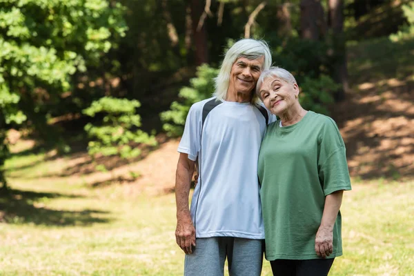 Cheerful Senior Couple Sportswear Hugging Green Park — Stock fotografie