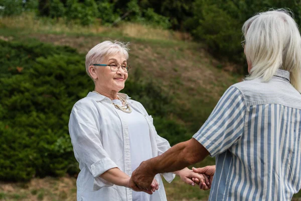 Happy Senior Woman Glasses Holding Hands Husband Striped Shirt Park — Foto de Stock