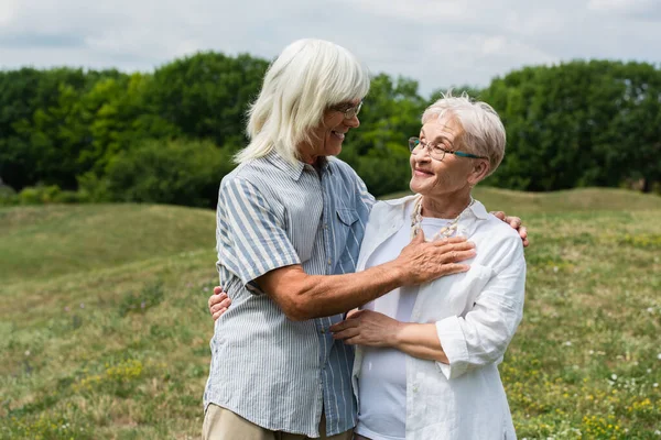 Smiling Senior Couple Glasses Hugging Looking Each Other Green Hill — Zdjęcie stockowe