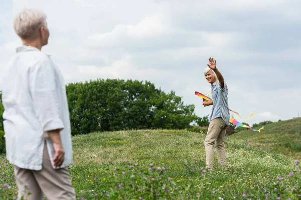 Happy Senior Man Casual Clothes Holding Kite Waving Hand Wife — Stockfoto