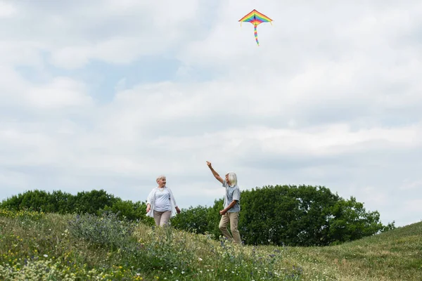 Happy Senior Couple Casual Clothes Playing Kite Green Hill – stockfoto