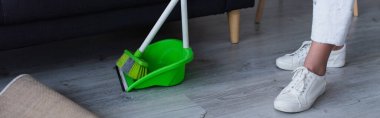 broom and scoop near cropped woman in white sneakers, banner