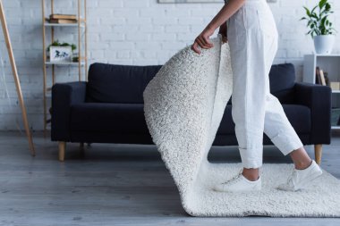 Cropped view of woman taking carpet while cleaning at home 