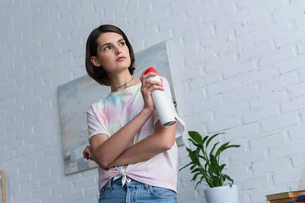 Low angle view of woman holding air freshener in living room