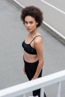 high angle view of african american woman in black sports bra looking at camera