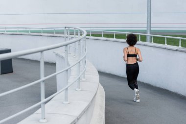 back view of brunette african american sportswoman running on stadium