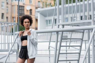 young african american woman in white sports jacket looking away on stadium