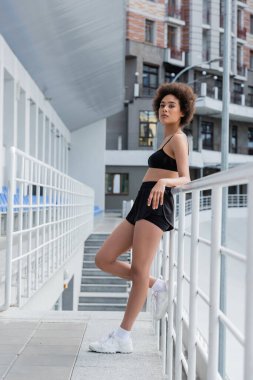 African american sportswoman standing near railing on stadium at daytime 