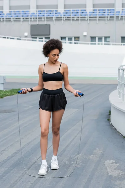 African american sportswoman holding jump rope on stadium