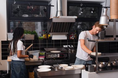 young multiethnic volunteers in t-shirts cooking together in kitchen