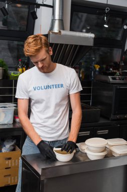 redhead volunteer covering bowl with plastic cup in kitchen 