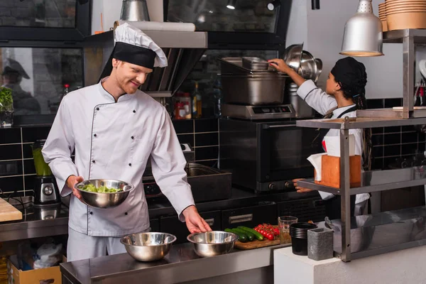 Cheerful Chef Holding Bowl Salad Vegetables African American Sous Chef — Stock Photo, Image