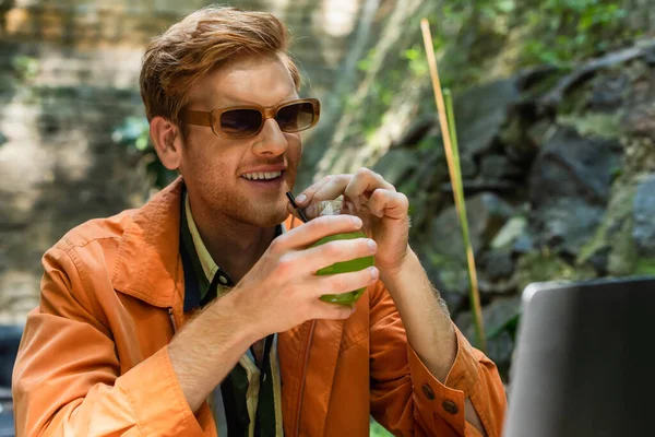 Cheerful Redhead Freelancer Sunglasses Holding Glass Cocktail Laptop Outdoor Terrace —  Fotos de Stock