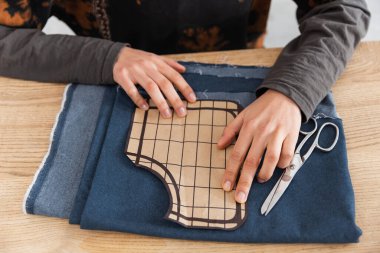 Cropped view of african american craftswoman holding sewing pattern near cloth 