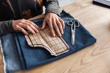 Cropped view of african american designer holding sewing pattern near cloth and scissors  clipart