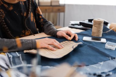 Cropped view of african american designer fastening sewing pattern on cloth in workshop 