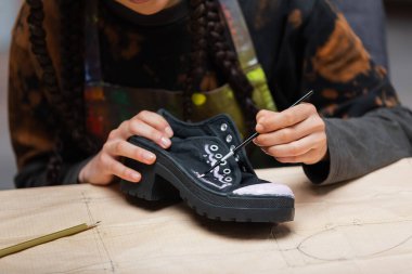 Cropped view of african american craftswoman painting on shoe on sewing pattern in workshop  clipart