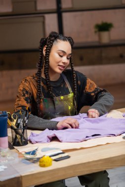 Cheerful african american designer holding cloth in workshop 