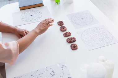 high angle view of cropped astrologist near star charts and clay runes on table